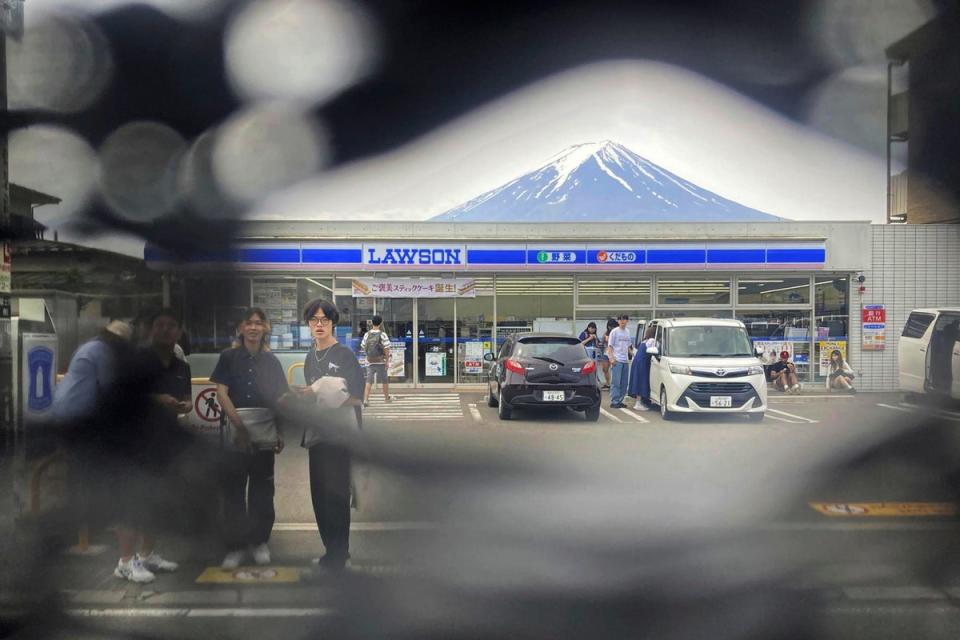 Mount Fuji is seen through a hole on a black screen installed across from a convenience store in Fujikawaguchiko town in central Japan (AP)