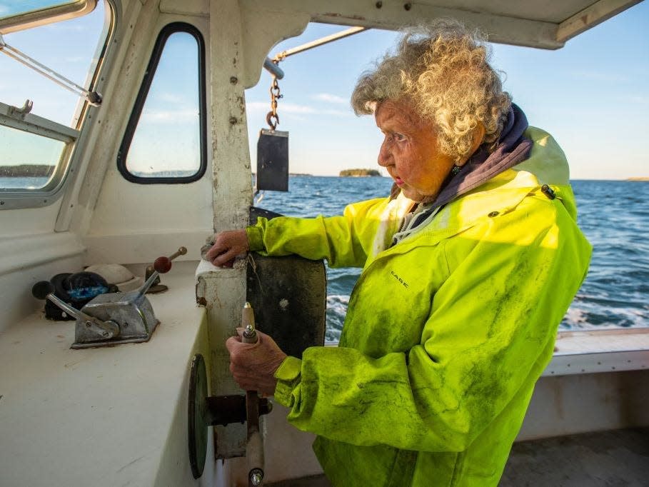 An older woman pilots a lobster boat.