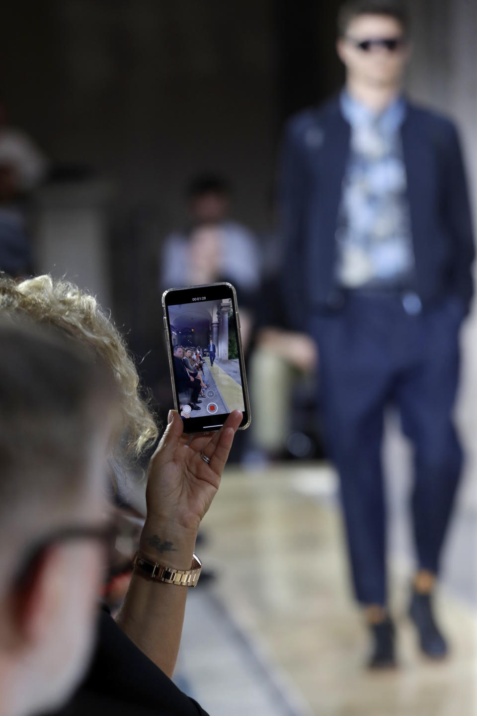 A model is recorded by a spectator wearing a creation as part of the Armani men's Spring-Summer 2020 collection, unveiled during the fashion week, in Milan, Italy, Monday, June 17, 2019. (AP Photo/Luca Bruno)