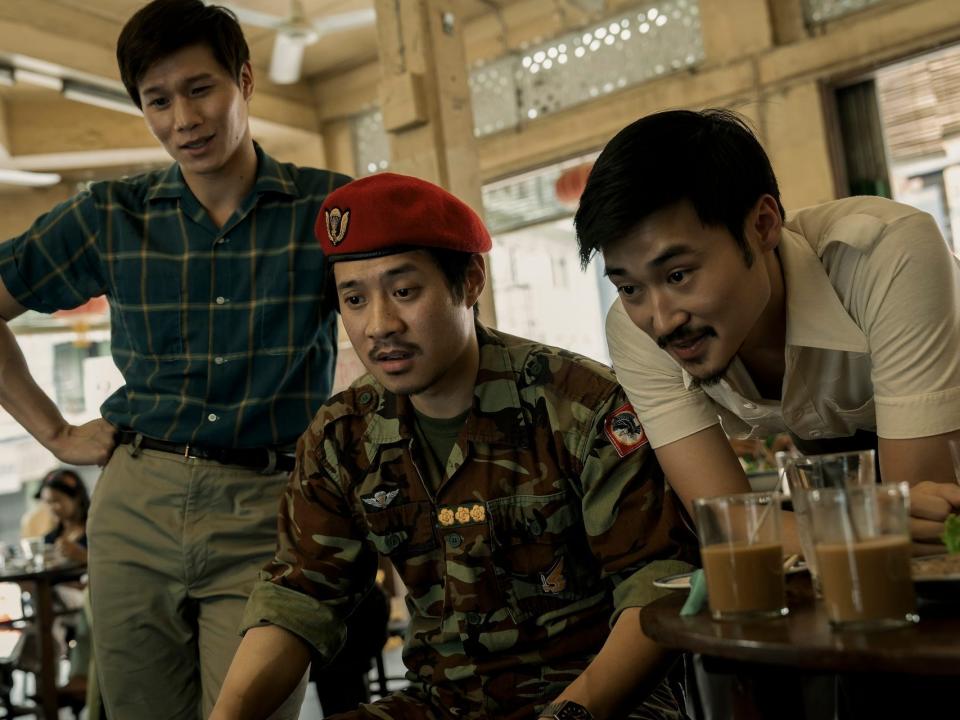hoa xuande, fred nguyen khan, duy nguyen standing in a restaurant near a table with coffee. the man in the middle is wearing a military uniform and red beret