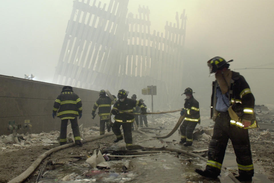 FILE - In this Sept. 11, 2001, file photo, firefighters work beneath the destroyed mullions, the vertical struts that once faced the outer walls of the World Trade Center towers, after a terrorist attack on the twin towers in New York. Sept. 11 victims’ relatives are greeting the news of President Donald Trump’s now-canceled plan for secret talks with Afghanistan’s Taliban insurgents with mixed feelings. (AP Photo/Mark Lennihan, File)
