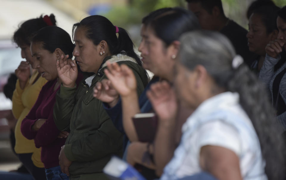 Yolanda Olivares, mother of Yovani and Jair Valencia Olivares, prays in front of an improvised altar with the photographs of her missing children, in front of her home in San Marcos Atexquilapan, Veracruz state, Mexico, Thursday, June 30, 2022. Neighbors prayed for the youths who are missing after confirming that they were traveling in the abandoned trailer in San Antonio, Texas, where more than 50 bodies of migrants were found. (AP Photo/Yerania Rolon)