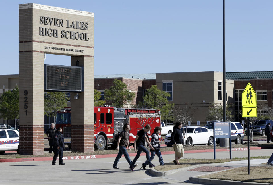 Students pass by Seven Lakes High School after being evacuated and released from school for the day Monday, Jan. 13, 2014, in Katy, Texas. A bomb squad was called to the school after a potentially explosive device was found. (AP Photo/Pat Sullivan)