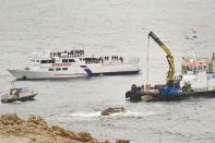 Workers place part of the "Le Scole" rock which was hit by the Costa Concordia cruise ship off the Tuscan Island Isola del Giglio, Italy, Sunday, Jan. 13, 2013. Survivors of the Costa Concordia shipwreck and relatives of the 32 people who died marked the first anniversary of the grounding Sunday. The first event of Sunday's daylong commemoration was the return to the sea of part of the massive rock that tore into the hull of the 112,000-ton ocean liner on Jan. 13, 2012 and remained embedded as the vessel capsized along with its 4,200 passengers and crew. (AP Photo/Antonello Nusca)