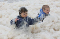 Children play with ocean foam in Burleigh Heads as Queensland experiences severe rains and flooding from Tropical Cyclone Oswald on January 28, 2013 in Gold Coast, Australia. Hundreds have been evacuated from the towns of Gladstone and Bunderberg while the rest of Queensland braces for more flooding. (Photo by Chris Hyde/Getty Images)