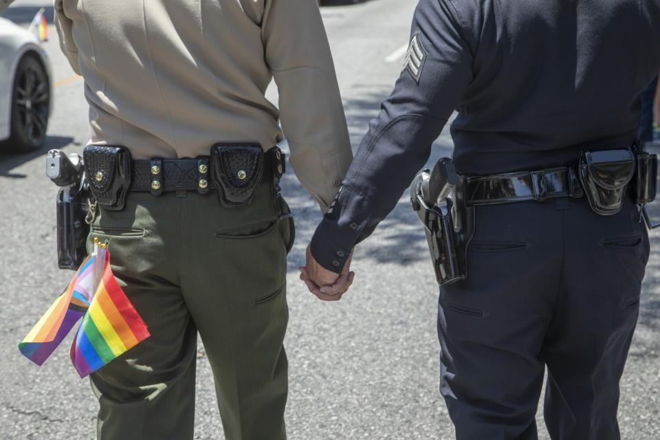 Two people in law enforcement uniforms hold hands