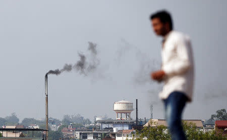 A man stands on a hill as smoke emits from a chimney of a leather tannery at an industrial area in Kanpur, India, May 4, 2018. Picture taken May 4, 2018. REUTERS/Adnan Abidi