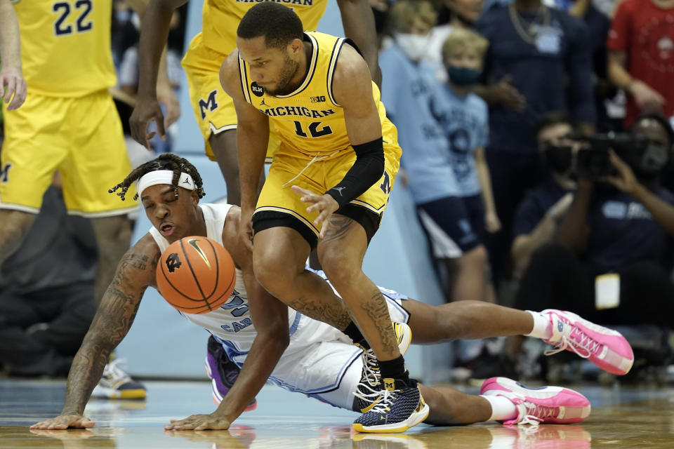 North Carolina forward Armando Bacot falls while chasing the ball with Michigan guard DeVante' Jones (12) during the first half of an NCAA college basketball game in Chapel Hill, N.C., Wednesday, Dec. 1, 2021. (AP Photo/Gerry Broome)