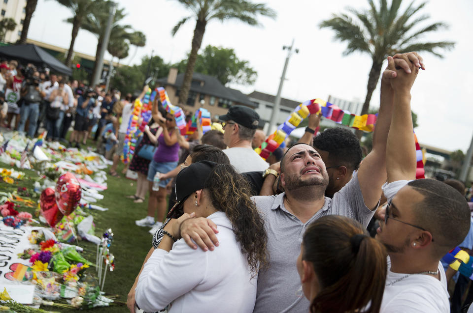 FILE - Jose Hernandez, center, joins hands with Victor Baez, right, as they mourn the loss of their friends Amanda Alvear and Mercedez Flores who were killed in the mass shooting at the Pulse nightclub, as they visit a makeshift memorial, Monday, June 13, 2016, in Orlando, Fla. (AP Photo/David Goldman, File)