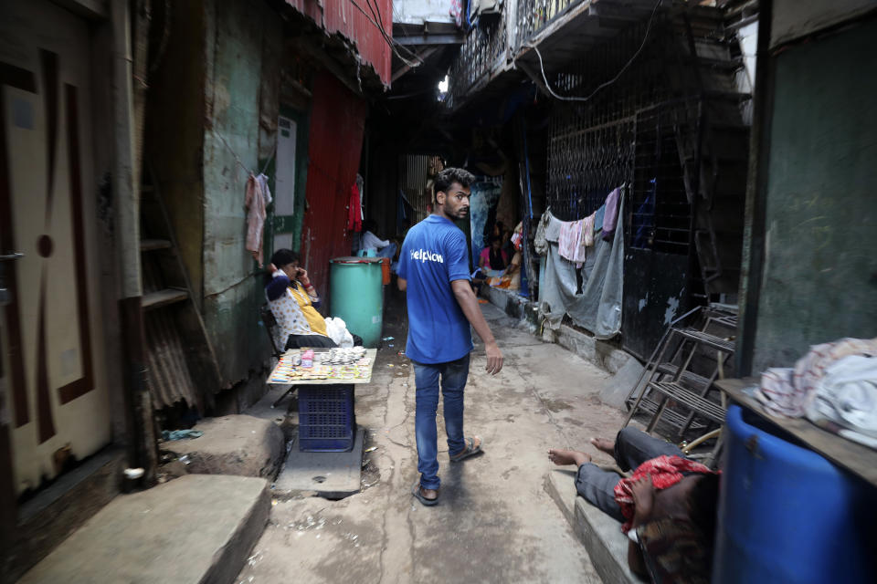 Izhaar Hussain Shaikh, center, an ambulance driver who works for HelpNow, an initiative to help the stretched services of first responders, walks in a lane outside their house in a slum as he arrives for a late lunch in Mumbai, India May 29, 2020. It’s an exhausting job and Shaikh's daily shifts are grueling, sometimes even stretching to 16 hours. For a city that has a history of shortage of ambulances and where coronavirus pandemic has claimed hundreds of lives, putting the health care system under immense strain, every help counts. (AP Photo/Rafiq Maqbool)