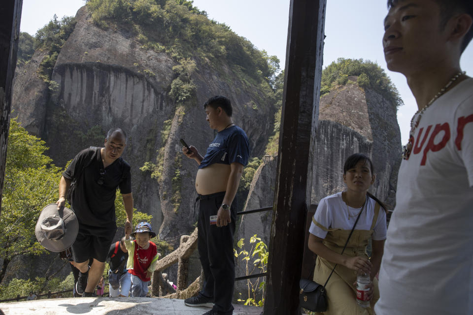 Visitors rest in a pavilion during a climb up Tianyou peak in Wuyishan in eastern China's Fujian province on Wednesday, Aug. 14, 2019. (AP Photo/Ng Han Guan)