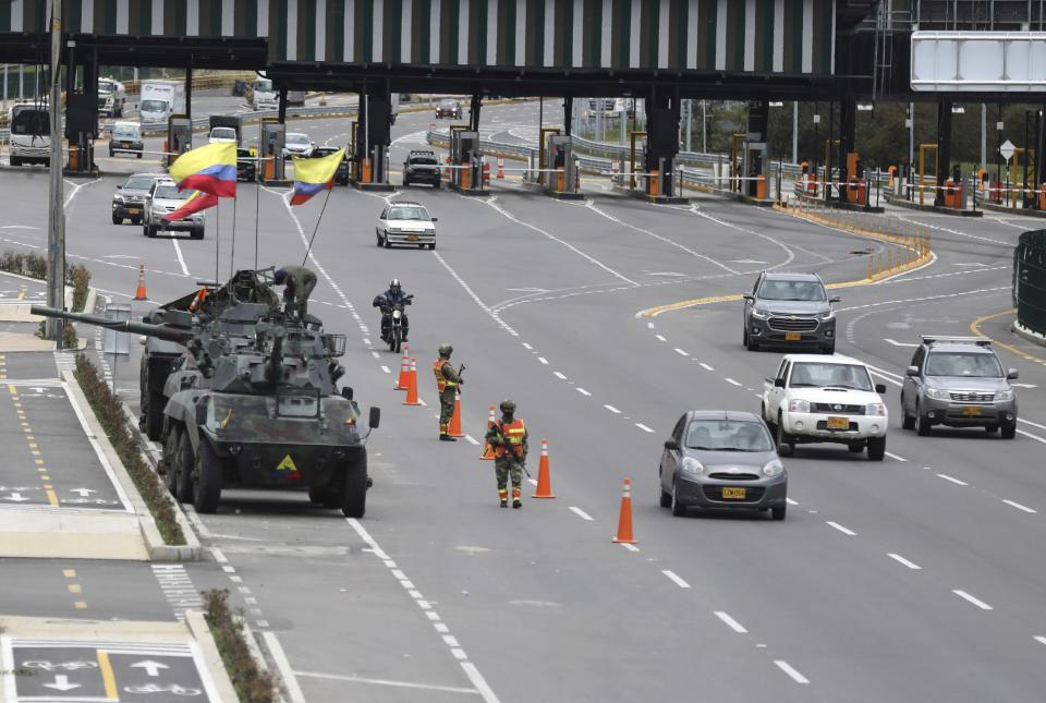 Soldiers and army tanks guard toll booths to keep protesters from damaging them, on the outskirts of Bogota, Colombia, Tuesday, May 4, 2021. Colombia’s finance minister resigned on Monday following five days of protests over a tax reform proposal that left at least 17 dead. (AP Photo/Fernando Vergara)