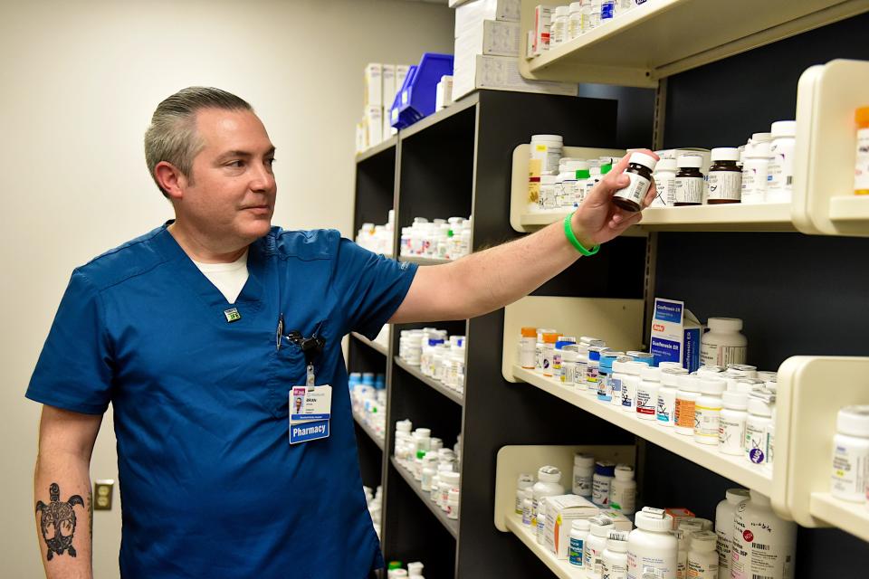 Brian George pulls a bottle from the shelf inside of the pharmacies at OhioHealth Mansfield Hospital.