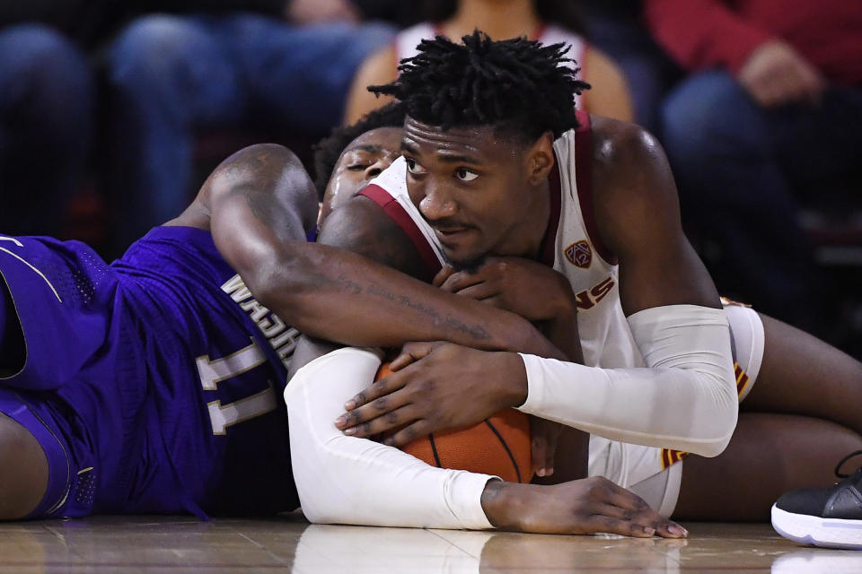 Washington guard Nahziah Carter, left, and Southern California guard Jonah Mathews tie up the ball during the first half of an NCAA college basketball game Thursday, Feb. 13, 2020, in Los Angeles. (AP Photo/Mark J. Terrill)