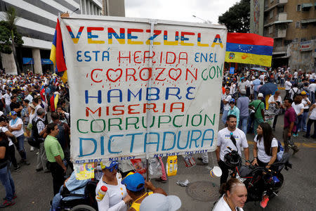 FILE PHOTO: Opposition supporters rally against President Nicolas Maduro carrying a sign that reads "Venezuela is wounded in the heart with hunger, misery, corruption and dictatorship", in Caracas, Venezuela May 10, 2017. REUTERS/Carlos Garcia Rawlins/File Photo