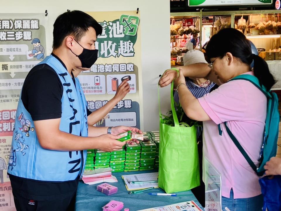 民眾自備購物袋買菜，與現場工作人員領取20元抵用券及宣導品。（圖：張亦呈攝）