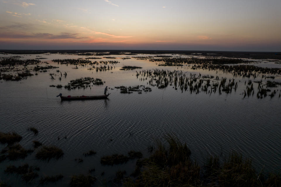 The sun sets as an Iraqi fishermen heads out on his boat in the Chibayish marshes of southern Iraq, in Dhi Qar, Iraq, Saturday, Nov. 19, 2022. (AP Photo Anmar Khalil)