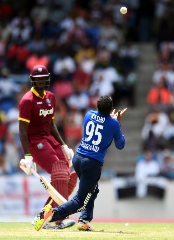 England's cricketer Adil Rashid (R) takes a catch to dismiss West Indies cricket team captain Jason Holder (back) during the second of the three-match One Day International series between England and West Indies on March 5, 2017