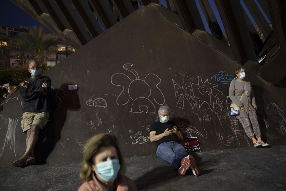 People wearing protective face masks amid concerns over the country's coronavirus outbreak, take part in a protest against Prime Minister Benjamin Netanyahu in Tel Aviv, Israel, Sunday, April 19, 2020. More than 2,000 people took to the streets on Sunday, demonstrating against Prime Minister Benjamin Netanyahu's attempts to form an "emergency" government with his chief rival and accusing him of using the coronavirus crisis to escape prosecution on corruption charges. (AP Photo/Oded Balilty)