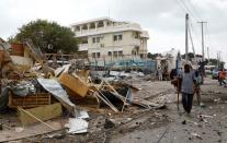 Civilians clear the scene after a car exploded in a suicide attack near Mucassar primary and secondary school in Hodan district of Mogadishu