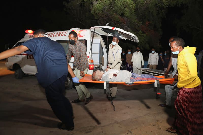 People assist an injured person outside Madina Hospital after a blast at the Luul Yemeni restaurant near the port in Mogadishu