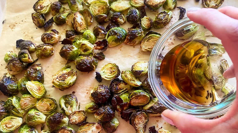 Roast Brussels sprouts pouring maple syrup from bowl