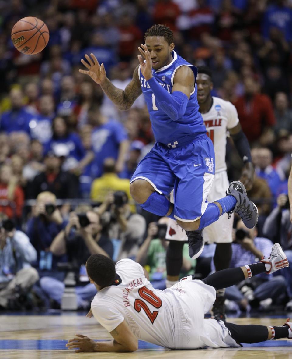 Kentucky's James Young (1) leaps over Louisville's Wayne Blackshear (20) as he passes the ball during the first half of an NCAA Midwest Regional semifinal college basketball tournament game Friday, March 28, 2014, in Indianapolis. (AP Photo/David J. Phillip)