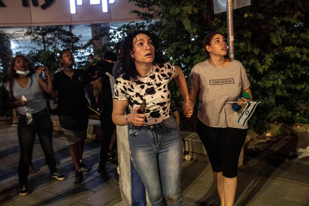 Jewish nationalist demonstrators look at a barrage of rockets fired from the Gaza Strip toward central Israel in the Israeli town of Ramla on Tuesday, May 11, 2021. The protesters had gathered in an attempted show of strength in a predominantly Arab neighborhood.