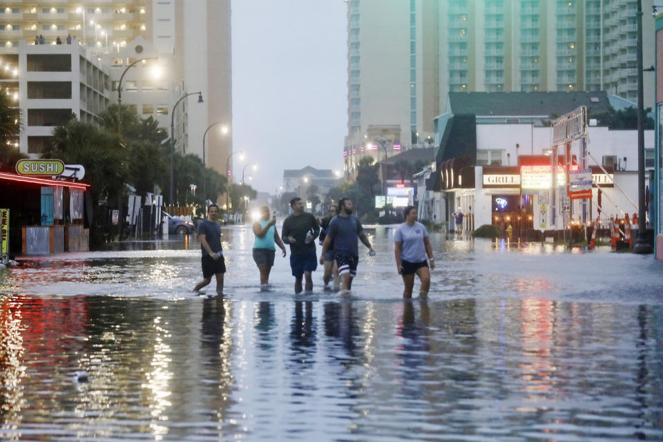 People walk up a flooded Ocean Boulevard in North Myrtle Beach, S.C. on Aug. 30, 2023 after the passage of Hurricane Idalia.  (Jason Lee / The Sun via AP)