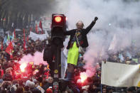 A man stands on a traffic light during a demonstration in Paris, Thursday, Dec. 5, 2019. The Eiffel Tower shut down, France's vaunted high-speed trains stood still and several thousand protesters marched through Paris as unions launched open-ended, nationwide strikes Thursday over the government's plan to overhaul the retirement system. (AP Photo/Thibault Camus)