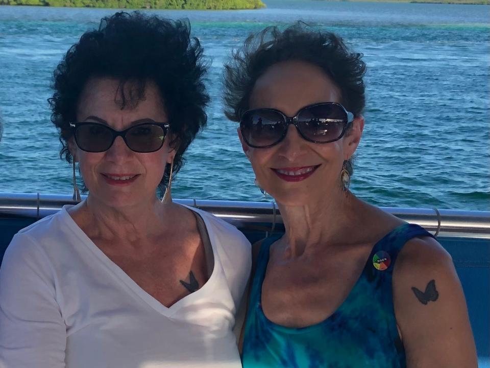 The author (right) and her sister, Diane, on a boat. They both are wearing sunglasses and both have butterfly tattoos.