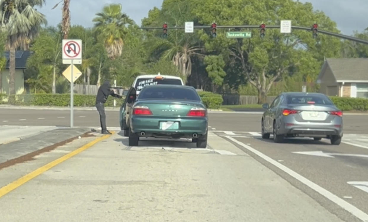 This screen grab taken from a nearby motorist's cellphone video and provided by the Seminole County Sheriff's Office shows a man pointing a gun at the driver of an SUV at an intersection just outside Winter Springs, Fla., Thursday, April 11, 2024. The suspect emerged from the car seen behind the SUV. (Courtesy of Seminole County Sheriff's Office via AP) / Credit: / AP