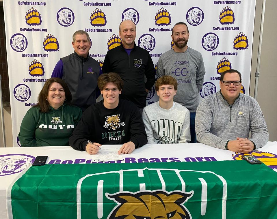 Jackson High School's Alex Zuckett is joined by (front row, left to right), his mother Wendy, his brother Elliot, his father John and (back row) Jackson coaches Kevin Walsh, Scott Akers and Marty Clement as he signs his letter of intent to run cross country and track at Ohio University.