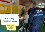 A policeman looks on a people participate in the first round of 2017 French presidential election in Vaulx-en-Velin, France, April 23, 2017. REUTERS/Emannuel Foudrot