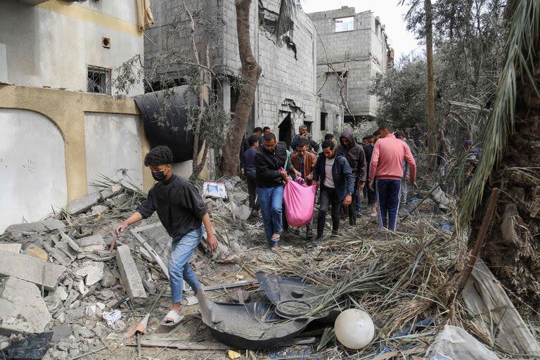 Palestinos transportan una víctima sacada de los escombros tras un bombardeo al oeste del campamento de refugiados de Nuseirat 