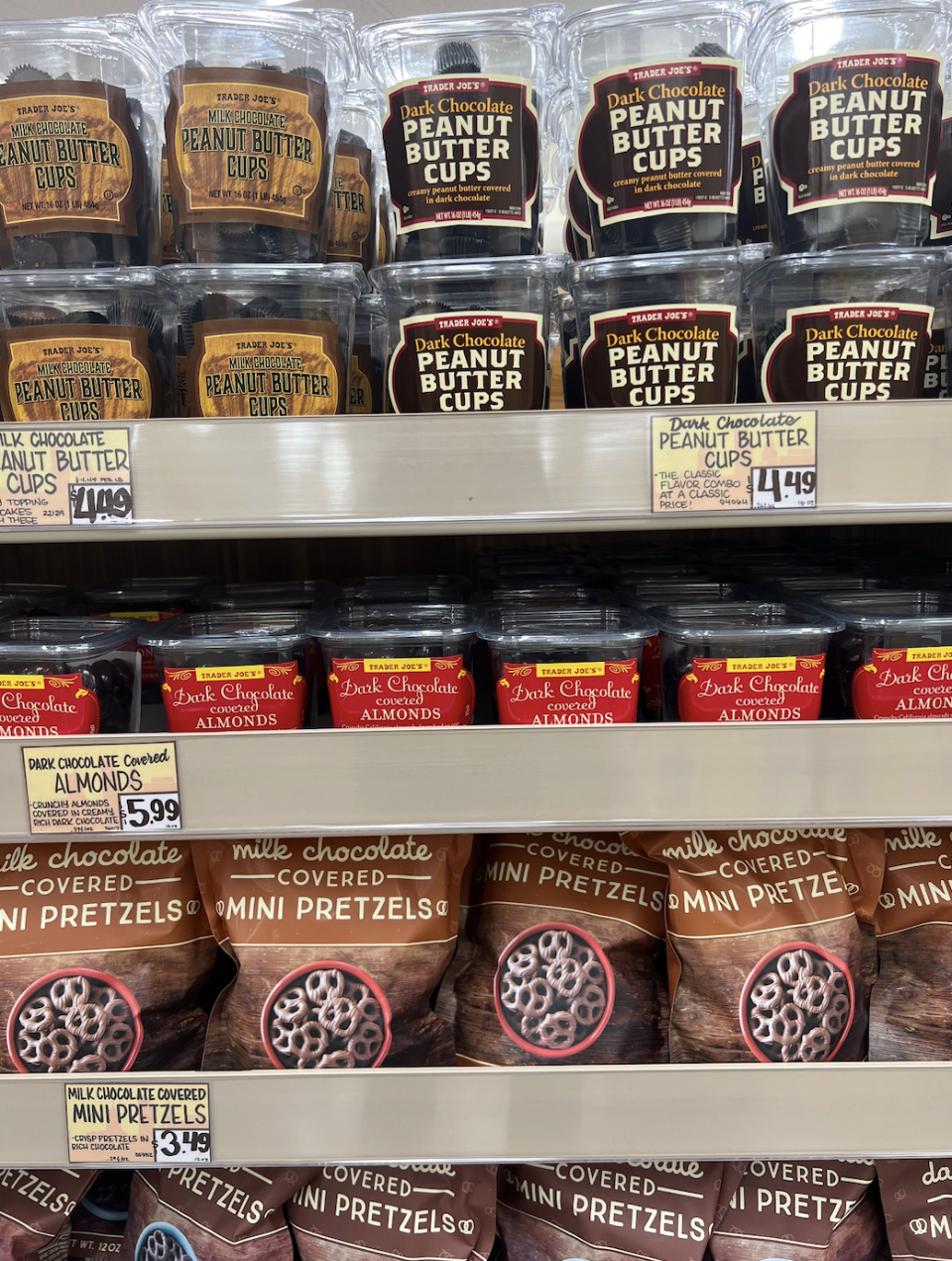 Shelves of various snack packages, including peanut butter cups, chocolate almonds, and chocolate-covered pretzels