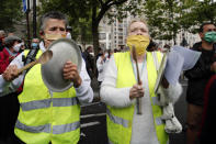 Demontrators wearing yellow vest support medical staff during a demonstration at the Robert Debre hospital in Paris, Thursday, June 4, 2020. French nurses and doctors demand better pay and a rethink of a once-renowned public health system that found itself quickly overwhelmed by tens of thousands of virus patients. (AP Photo/Francois Mori)