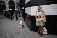 A woman, with the Belgium flag and a sign in French reading: "Freedom. Democracy" on her chest, stands next to anti riot police during an unauthorised demonstration against COVID-19 restrictive measures in Brussels, Sunday, Jan. 31, 2021. According to Belgian media around 200 people have been arrested for trying to join a protest against restrictive measures implemented in the country in order to fight the virus, such as a 10pm curfew or the closing of bars and restaurants. (AP Photo/Francisco Seco)