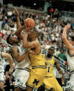 FILE - In this Feb. 3, 1993 file photo, Michigan's Juwan Howard, right, pushes against Michigan State's Dwayne Stephens as he goes up for a shot during the first half at Breslin Center in East Lansing, Mich. Howard will make his coaching debut in a heated rivalry when No. 12 Michigan plays at No. 14 Michigan State on Sunday, Jan. 5, 2020.(AP Photo/Lennox McLendon, File)