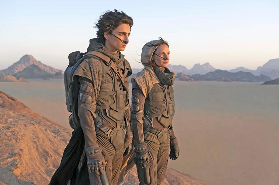 A mother and son stare at their destiny from a sand dune in a barren desert planet in “Dune”