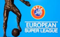 A metal figure of a football player with a ball is seen in front of the words "European Super League" and the UEFA logo in this illustration