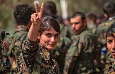 A female fighter of the US-backed Kurdish-led Syrian Democratic Forces (SDF) flashes the victory gesture while celebrating near the Omar oil field in the eastern Syrian Deir Ezzor province on March 23, 2019, after announcing the total elimination of the Islamic State (IS) group's last bastion in eastern Syria. - Credit: AFP