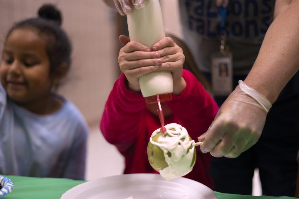 Jill Brems adds white chocolate to an apple at Whittier Elementary School in West Valley on Friday, Nov. 3, 2023. Brems earned the opportunity to participate in the activity by improving her attendance. | Laura Seitz, Deseret News