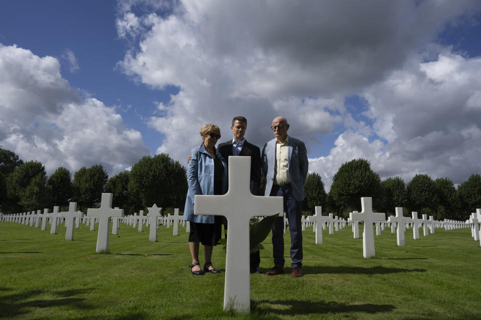 Eighty years after the liberation of the south of the Netherlands, Scott Taylor, center, Ton Hermes and Maria Kleijnen stand next to the grave of Scott's grandfather Second Lt. Royce Taylor, a bombardier with the 527 Bomb Squadron, at the Netherlands American Cemetery in Margraten, southern Netherlands, on Wednesday, Sept. 11, 2024. (AP Photo/Peter Dejong)