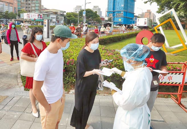 台灣新冠肺炎疫情持續升溫，台北市萬華區的民眾19日一早就在篩檢站外排隊等候領號碼牌，時間一到，護理人員依序發放號碼牌並耐心向民眾說明篩檢相關事宜。（劉宗龍攝）