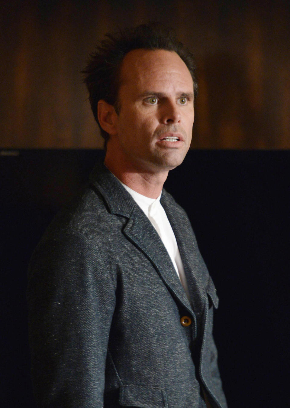 Walton Goggins in a grey blazer standing with an intense expression