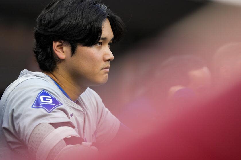 Los Angeles Dodgers' Shohei Ohtani stands in the dugout during the second inning of the team's baseball game against the Cincinnati Reds Friday, May 24, 2024, in Cincinnati. (AP Photo/Jeff Dean)