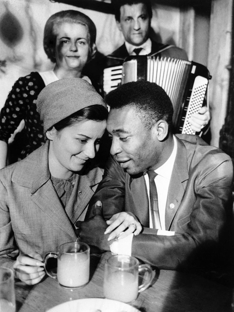 ARCHIVO - En esta foto del 5 de marzo de 1966, Pelé y su esposa Rosemarie escuchan a cantantes de Heurigen mientras beben vino en una taberna de Viena, Austria. (AP Foto, archivo)