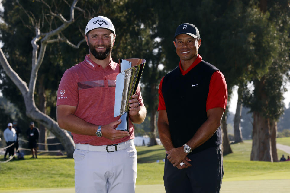 FILE - Jon Rahm, left, holds the winner's trophy next to Tiger Woods after winning the Genesis Invitational golf tournament at Riviera Country Club, Sunday, Feb. 19, 2023, in the Pacific Palisades area of Los Angeles. Rahm has been saying that he plays golf for history and for legacy, not for money. And now he's playing for the Saudi-funded LIV Golf League in a shocking departure from the PGA Tour. (AP Photo/Ryan Kang, File)