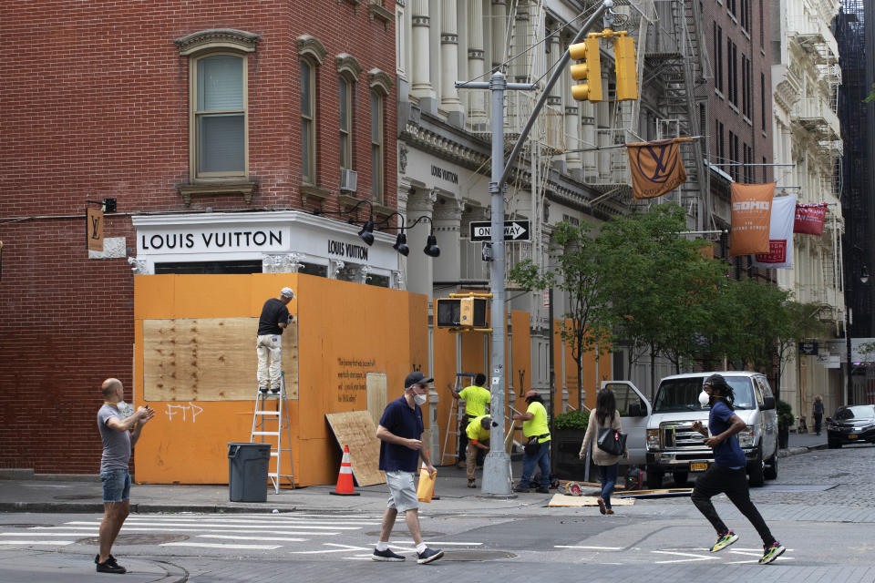 Workers board up windows of a Louis Vuitton store, Wednesday, June 3, 2020, in the SoHo neighborhood of New York. Protests resumed Tuesday during the day over the death of George Floyd, a black man who died May 25 after being restrained by Minneapolis police in Minnesota. Thousands marched in parts of Manhattan and Brooklyn, as merchants boarded up their businesses. (AP Photo/Mark Lennihan)